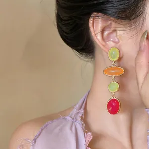 Close-up showing colorful resin oval drop earrings in a vintage baroque design on a model