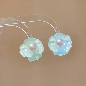 Detailed macro view of mint green flower earrings with white pearl center on a clear stand