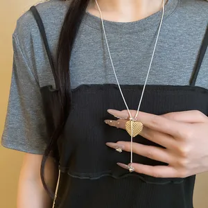 Detail of a hollow heart pendant adjustable necklace worn over a casual gray and black top.