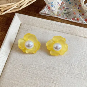 Close-up of fresh yellow flower stud earrings with elegant pearl center on a tray