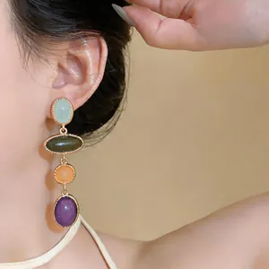 Close-up of elegant court-style drop earrings with colorful oval resin stones