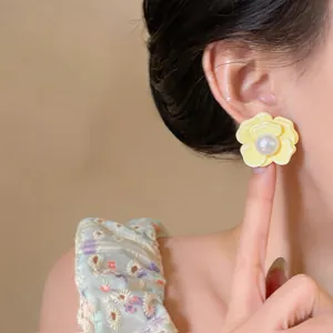 Detailed view of yellow flower earring with pearl on ear for elegant Korean style