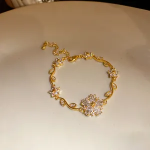 Vue macro d'un bracelet plaqué or 18 carats avec détails de fleurs et feuilles en zircon.
