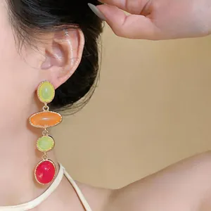 Close-up of vintage resin drop earrings featuring colorful oval beads in gold setting