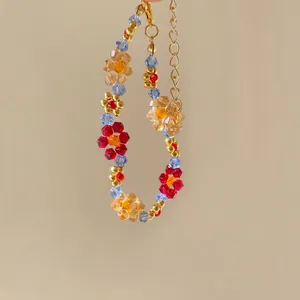 Close-up of colorful handmade beaded bracelet with floral crystal patterns and gold clasp.