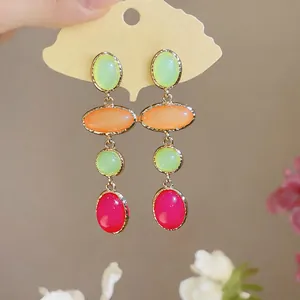 Macro detail of colorful resin oval modules on court style drop earrings with silver pins
