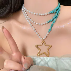 Detalle de collar multicapa con perlas, piedras turquesas y colgante de estrella dorada