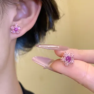 Detailed view of pink and purple rhinestone star earrings shown being worn and held