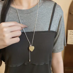 Macro view of gold heart-shaped openwork pendant on a delicate silver snake chain