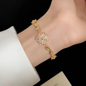 Détail d'un bracelet fleur plaqué or avec des pierres de zircon étincelantes sur un poignet.