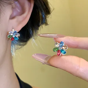 Detailed macro view of colorful rhinestone flower stud earrings worn on model ear