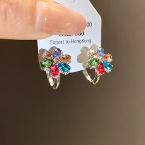 Close-up of flower earrings with vibrant multi-colored crystals on silver hoops.