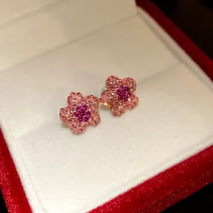 Macro detail of pink flower stud earrings with sparkling crystals in a velvet red jewelry box