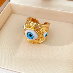 Close-up view of a chunky gold open ring featuring detailed blue resin evil eyes