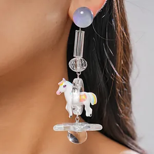 Detailed close-up showing a whimsical resin earring featuring a white pony and clear star.