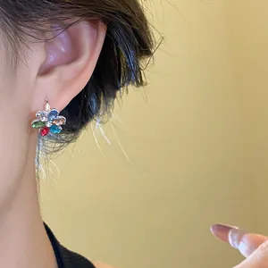 Close-up of exquisite multi-colored flower stud earring on ear for summer resort style.