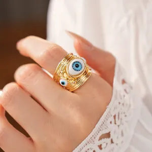 Detailed close-up of a gold-layered ring featuring resin evil eye motifs on a hand