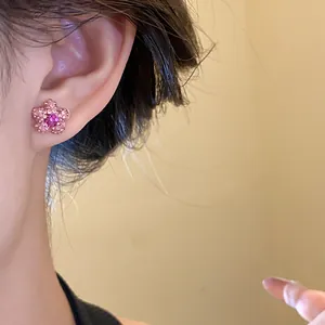 Macro detail shot of a pink star-shaped rhinestone stud earring worn on model's ear.