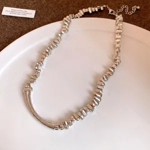 Fashionable silver-tone necklace with irregular blocky beads and a smooth curved center bar.