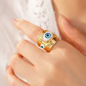 Close-up view of a unique gold evil eye resin ring on finger featuring a detailed blue eye design