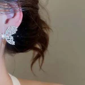 Boucles d'oreilles élégantes en forme d'aile de papillon avec perles et cristaux sur modèle.