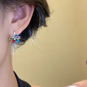 Close-up view of an elegant silver flower earring with colorful rhinestones worn by a model
