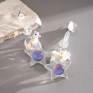 Macro view of dopamine resin unicorn and star earrings featuring silver needle studs
