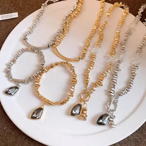 Close-up of irregular gold and silver bead necklaces featuring grey triangle pendants