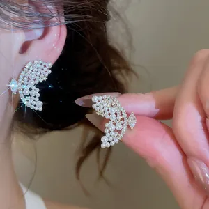 Gros plan d'élégantes boucles d'oreilles papillon évidées avec perles et cristaux
