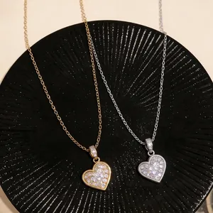 Elegante Herzanhänger in Gold und Silber mit funkelnden Zirkonen auf einem schwarzen Teller