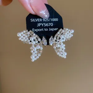 Vue détaillée de boucles d'oreilles papillon exquises avec perles et cristaux sur carte argent.