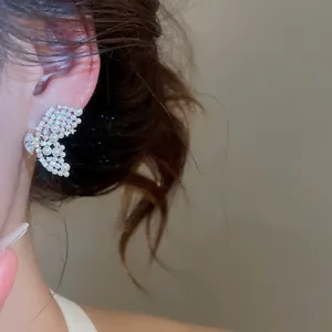 Gros plan de boucles d'oreilles papillon élégantes avec perles et diamants portées