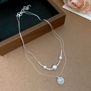 Close-up of double-layered necklace with star zircon pendant and pearls