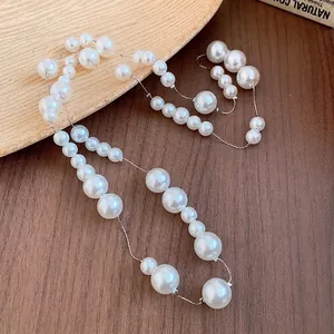 Elegant French vintage pearl necklace with varied bead sizes on a wooden background