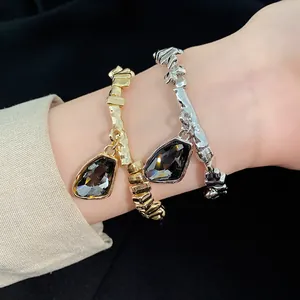 Close-up macro view of gold and silver bracelets featuring irregular dark stone pendants