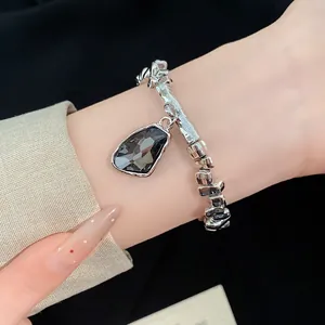 Close-up of a silver irregular bracelet with a dark gray geometric stone pendant