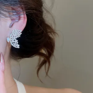 Gros plan d'une boucle d'oreille papillon élégante avec perles et strass sur l'oreille.