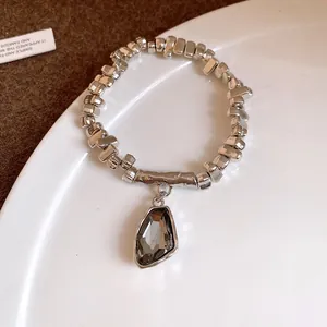 Elegant silver-toned beaded bracelet featuring an irregular faceted grey crystal pendant