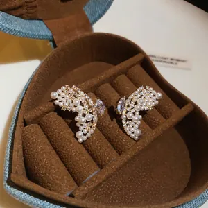 Gros plan détaillé de boucles d'oreilles papillon en perles dans une boîte en cœur