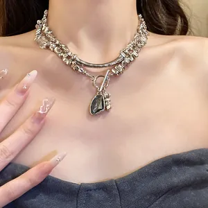 Close-up view of a stylish silver chain necklace with an irregular triangle pendant on a model