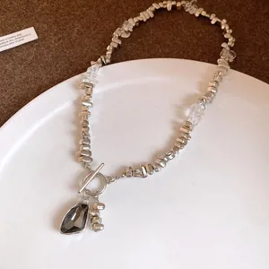 Macro detail view of a silver irregular bead necklace with a dark triangle pendant