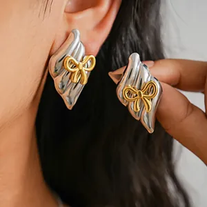 Close-up detail of vintage style two-tone metal bow earrings worn on a model's ear