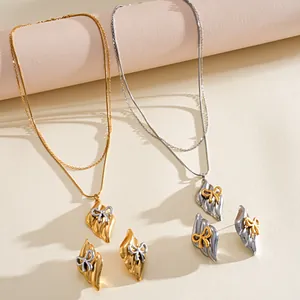 Detailed view of stainless steel jewelry set with textured metal and bow pendants