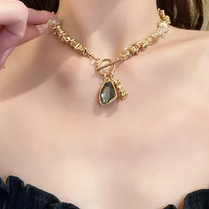 Close-up of elegant gold chain necklace with irregular grey crystal pendant on model