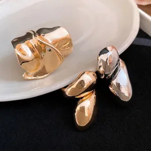 Irregular liquid metal rings in gold and silver finish with distorted water drop design.