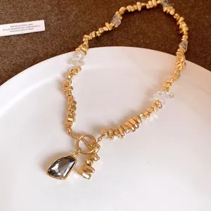 Detail of gold irregular bead necklace with a dark grey crystal triangle pendant
