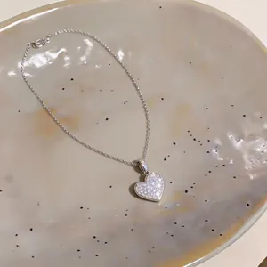 Detailansicht einer silbernen Herz-Halskette mit funkelnden Zirkonia-Steinen.