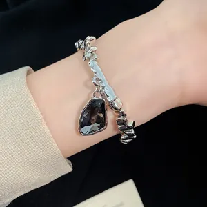 Detailed view of a minimalist silver-tone bracelet with a black triangular gemstone (82 chars)