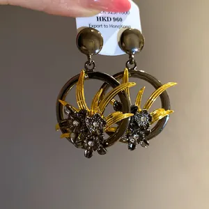 Detailed view of vintage hollow floral drop earrings with gold leaves and rhinestones