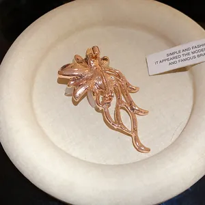 Vista posteriore dettagliata di un'elegante spilla a fiore in oro rosa su un vassoio crema.